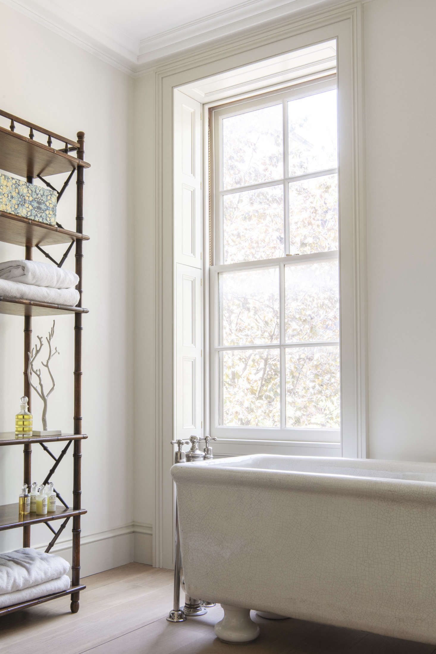 The tub’s faucets are original, newly restored to working order; note the tub’s crackle glaze. All of the windows in the house are new—”weight and chain, double hung with restoration glass,” specifies Lekwa. The front-facing rooms have custom pocket shutters: “The originals were American-style slatted but these are solid panels, per my request,” says the owner. She found the faux-bamboo mahogany shelves on Chairish.