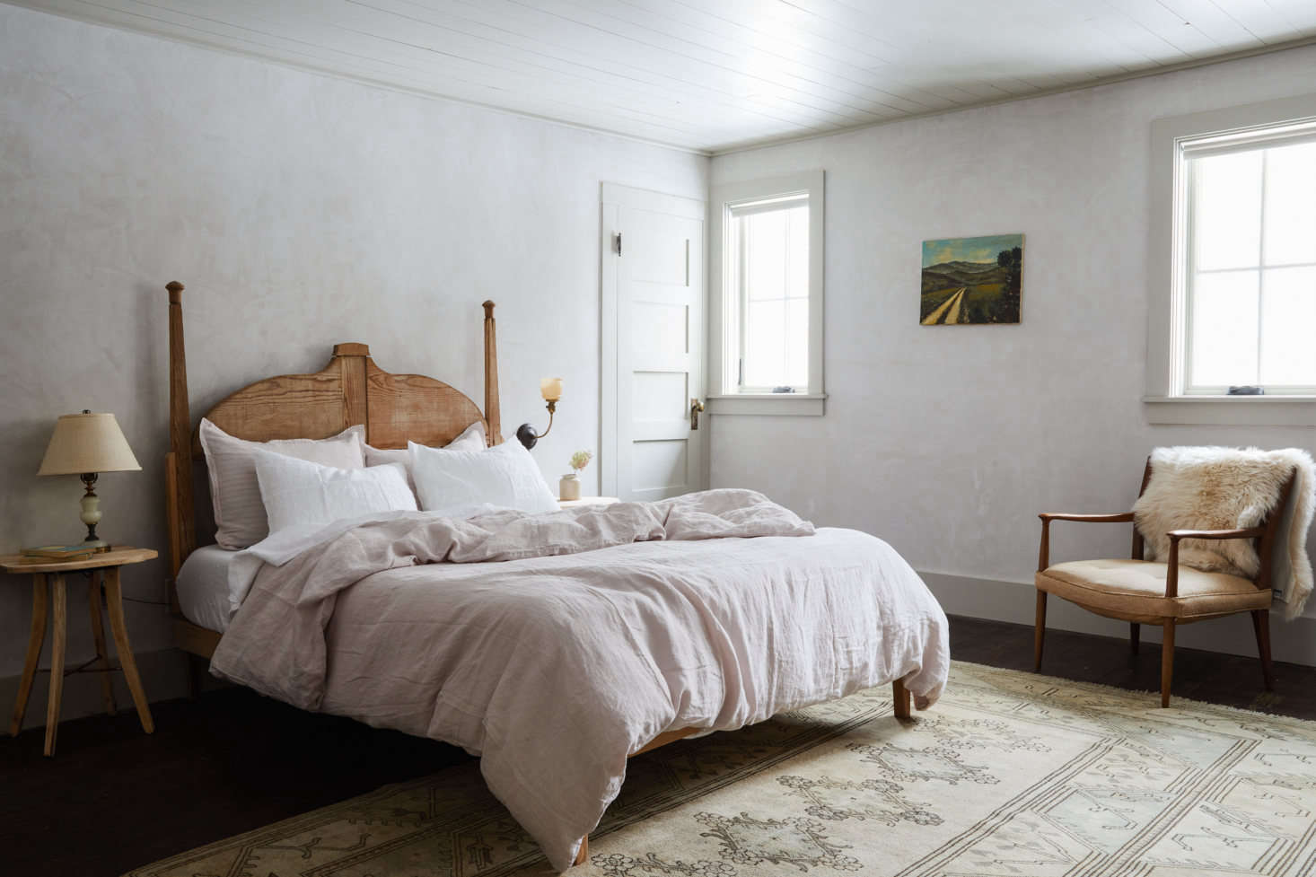 Soft gray walls plaster walls, a painted ceiling, and linen bedding by Parachute Home create a luminous atmosphere in the Trung bedroom.