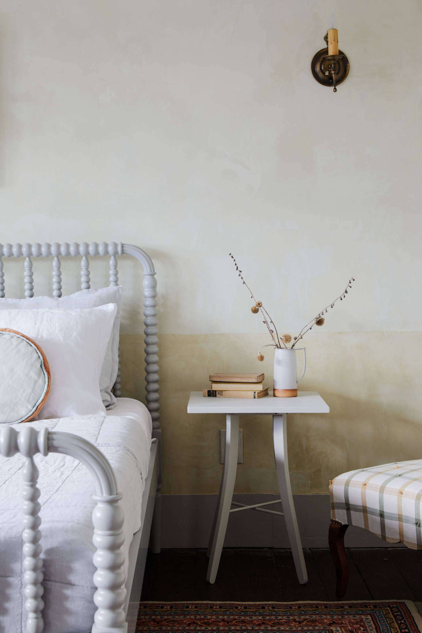 The yellow bedroom has duo-toned plaster complemented by a custom side table and Crate and Barrel Kids bed painted in Benjamin Moore Revere Pewter HC-