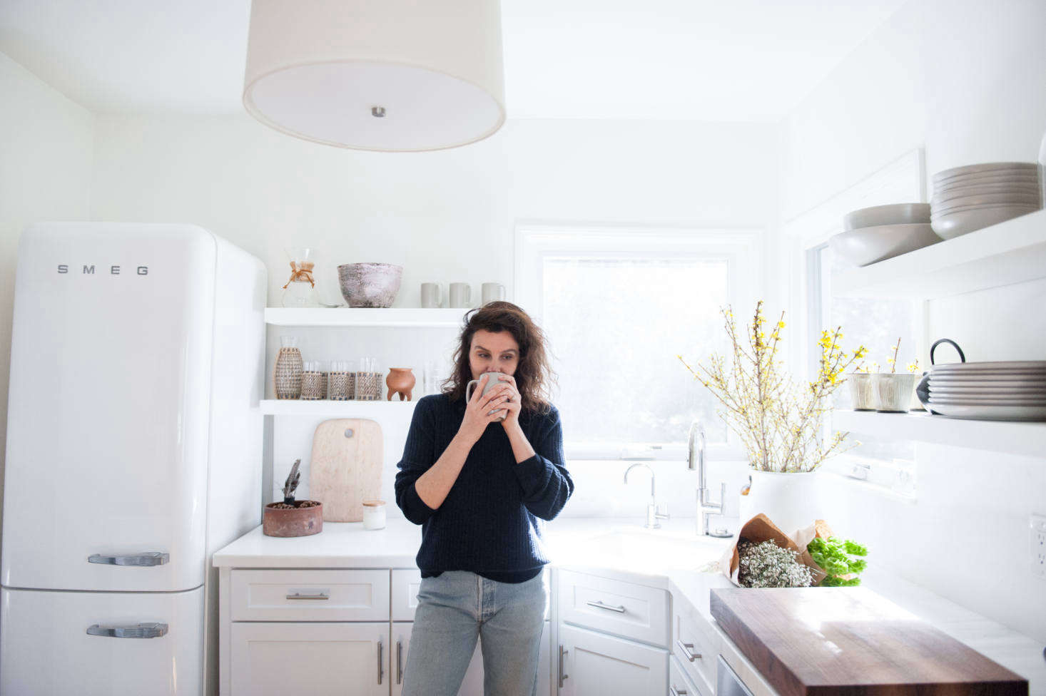 The kitchen was given a makeover using the existing cabinetry. “We replaced the upper cabinets with open shelves, brought in new appliances and hardware, and swapped the granite counter out for marble,” says Lauren.