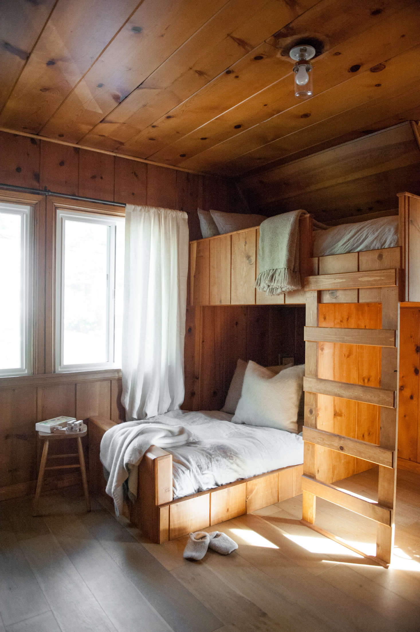 Lauren designed the custom bunk beds to continue the lines of the existing paneling.”The staggered configuration of bunks creates some space underneath,” she says. “The setup works with the shape of the room and was inspired by images of Scandinavian cabins and ski chalets.”