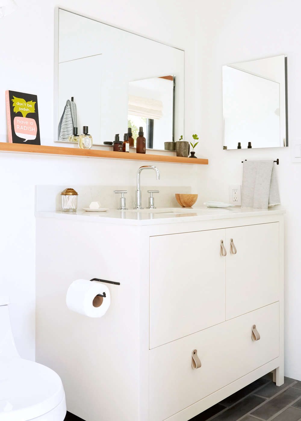 The toilet is the San Souci K-4007 in white from Kohler, and the Fog Linen Toilet Paper Holder is from Atomic Garden. The custom Douglas fir shelves (over the vanity and tub) were made by Christopher Faiss of Born and Built.