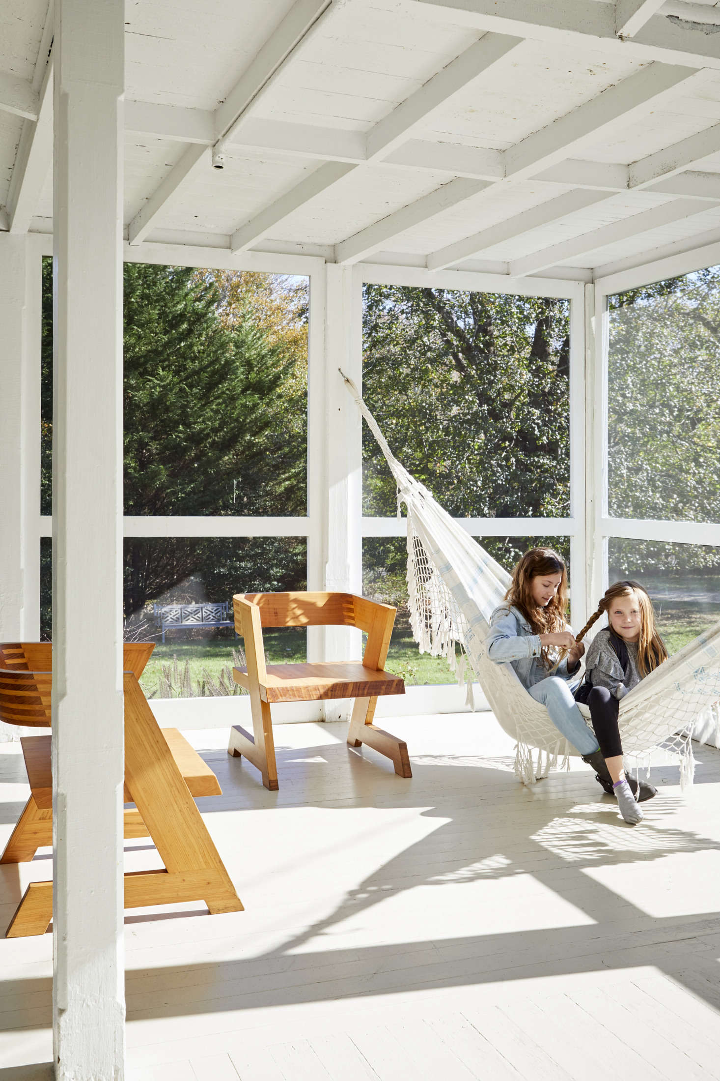 The Burden girls hang out on the screened porch in a hammock that the family brought back from a trip to Brazil. The Zigzag chairs are prototypes from Jonathan