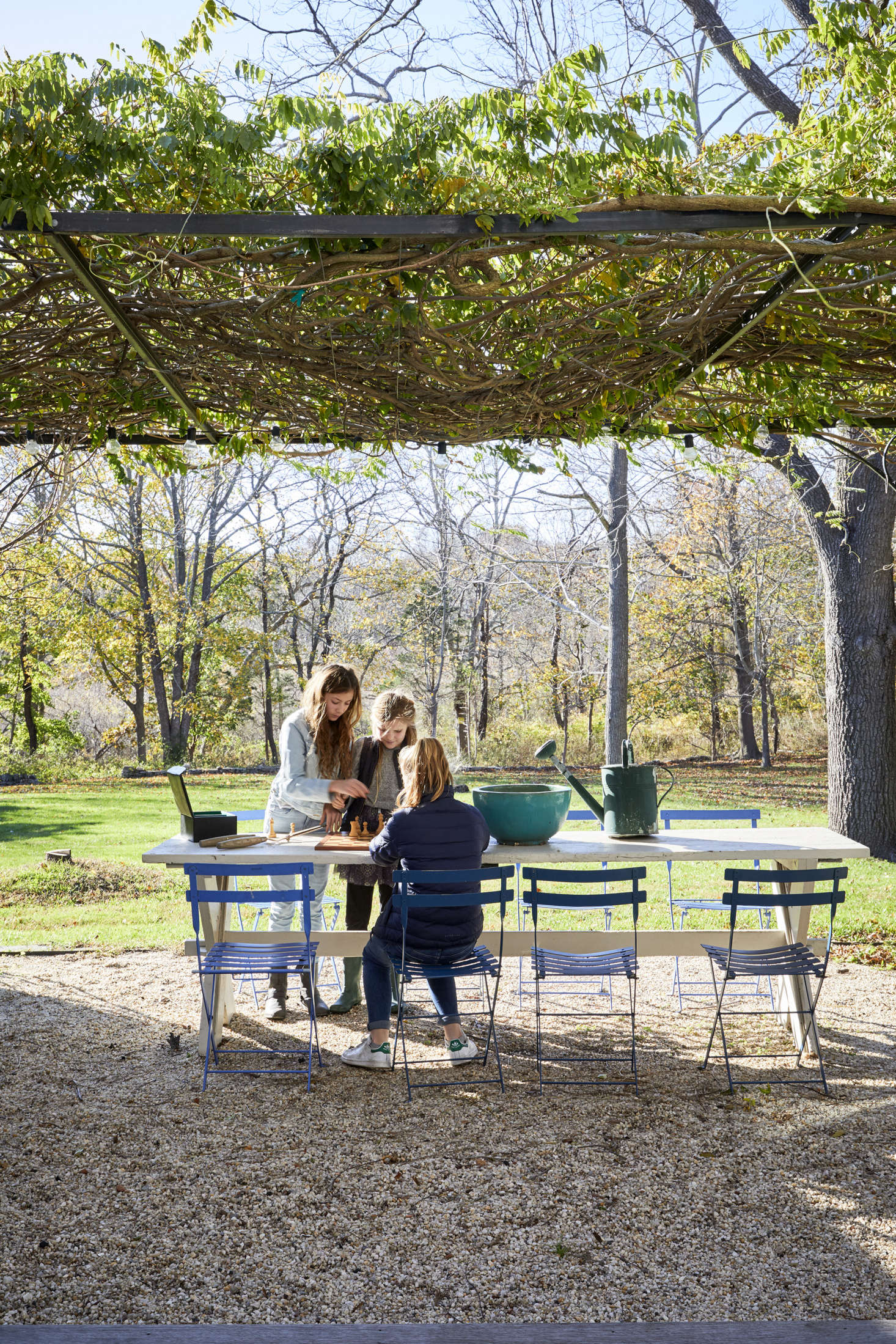 French doors in the back of the house open to a gravel patio shaded by a wisteria arbor: 