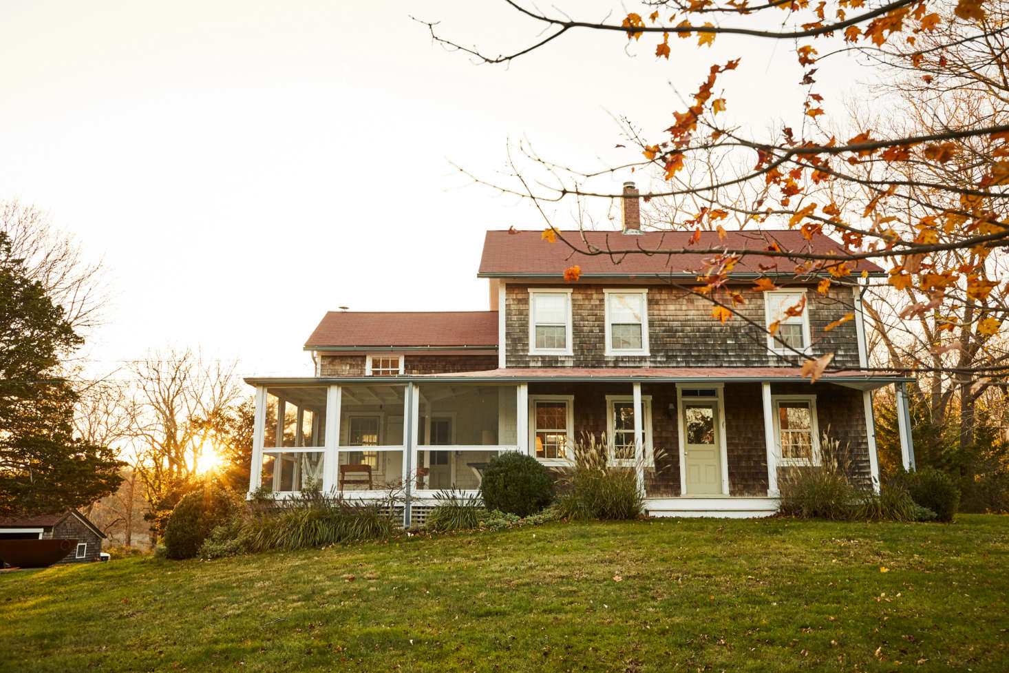 The mid-th century house sits atop a hill next to Coecles Harbor, where the family keeps their sailboat (scroll to the end for an aerial view of the property). The side porch was formerly boarded up and used for storage; the Burdens restored it and added copper screens. They also planted many more trees for privacy (scroll to the end for an aerial view) and introduced a long driveway that winds around the property and 