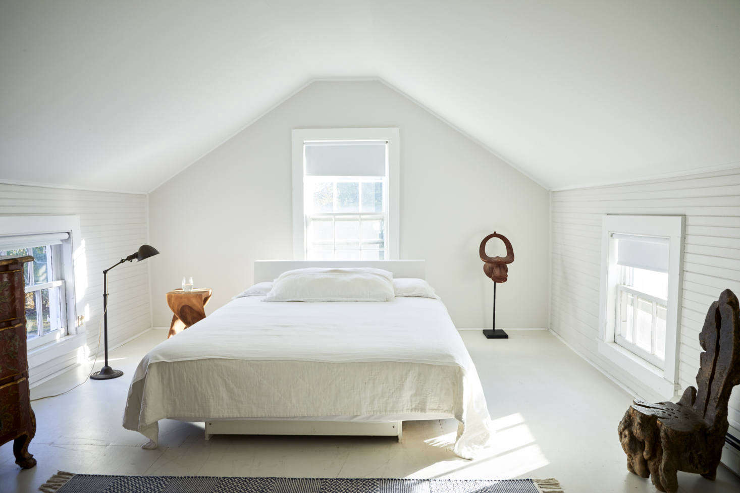 Set under the eaves, the master bedroom has a platform bed that Jonathan built from wood left over from the library shelves. It overlooks a large soaking tub at the other end of the room.
