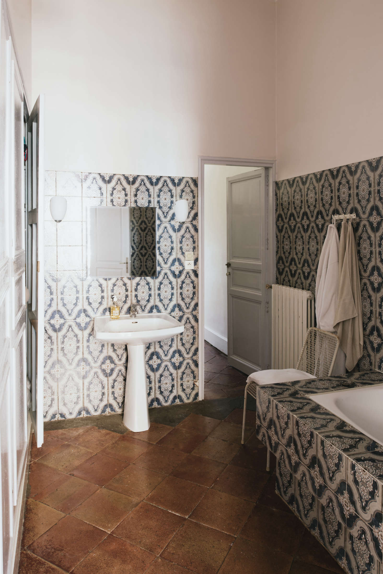 A bathroom with intricately patterned tile and a terra cotta floor.