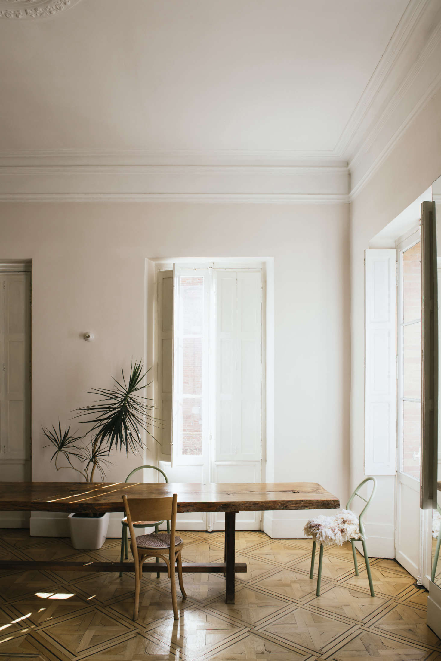 Mismatched chairs Sathal has collected surround the table. The tiny white wall sconces that appear throughout the house are from Zangra.