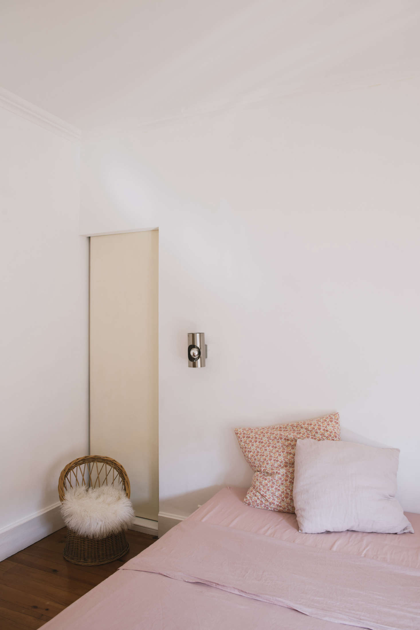 A bedroom with pink linens and silver wall sconces. “I make all of the pillowcases and some duvet covers,” Sathal says. “Every sheepskin was bought for the birth of my children.”