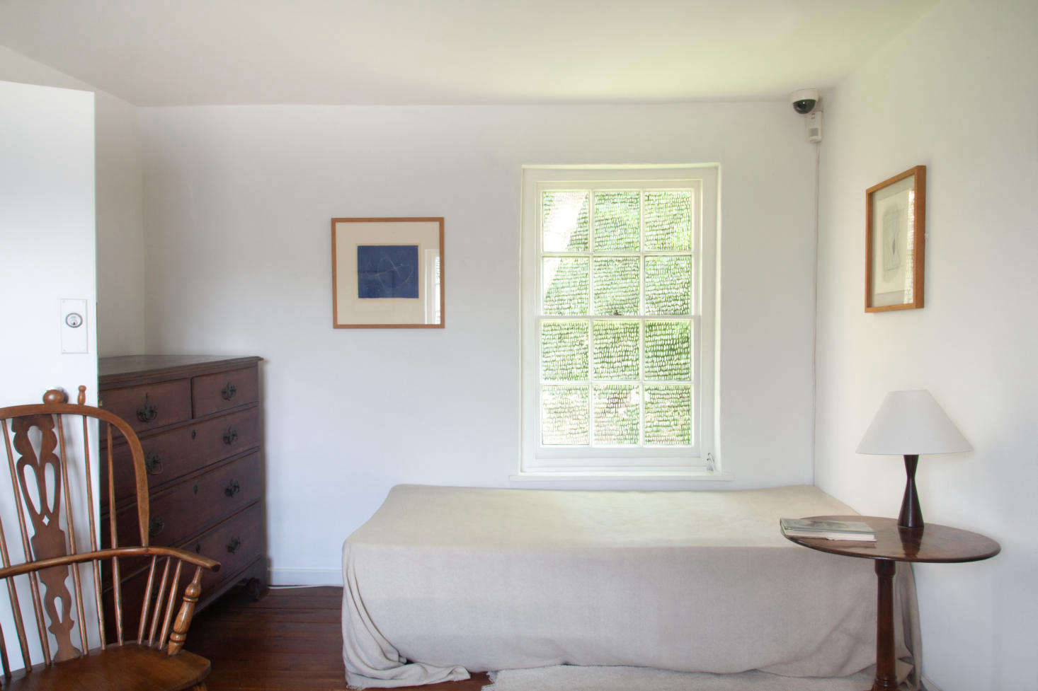 The upstairs bedroom has a basic mattress and frame with a large linen sheet tossed over the top and barely tucked in at the bottom.