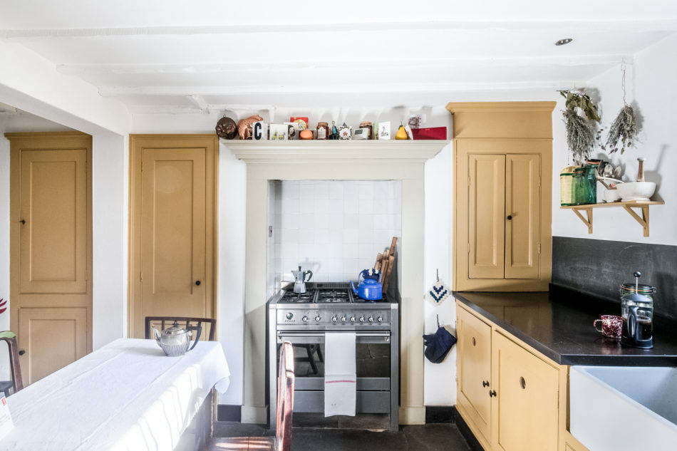The modest kitchen on the ground floor features ochre paint on the cabinets, a color that shows up again in other parts of the home.