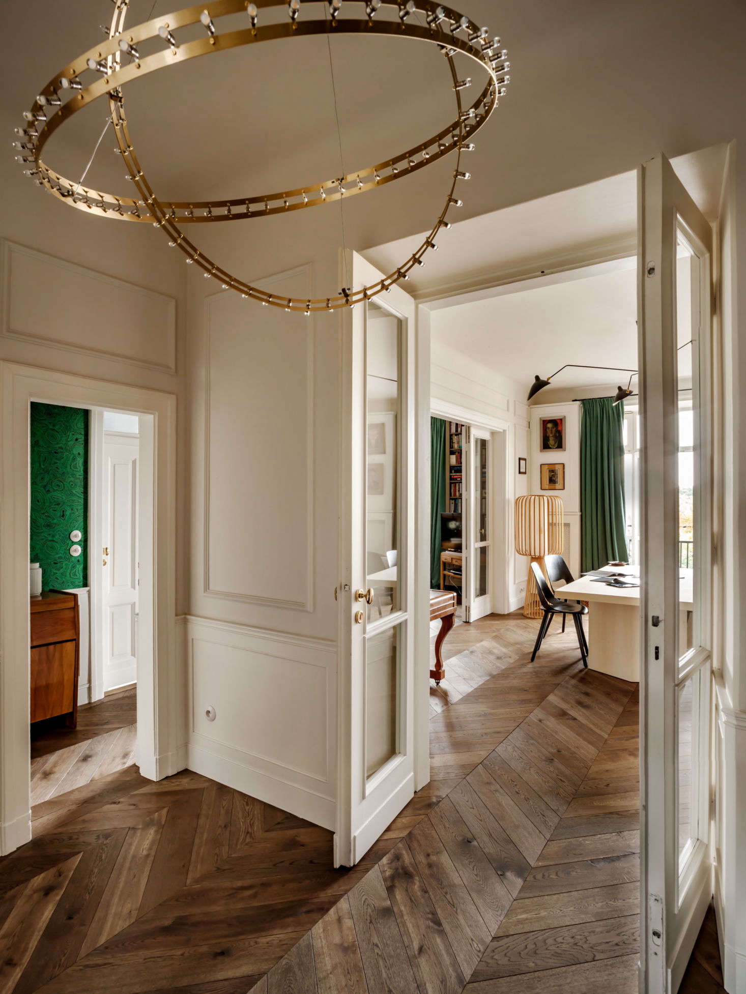 A peek, from the entry, into the dining room. Before Chrapka even thinks about the interior design, she focuses on the layout and fundamentals. “I try to keep or recreate the original layout always when it’s possible. That gives the feeling of a classical interior. I usually find the original plans from the ’20s or ’30s and try to adapt it to modern needs.” she says. The brass Citadel chandelier is from Quasar.
