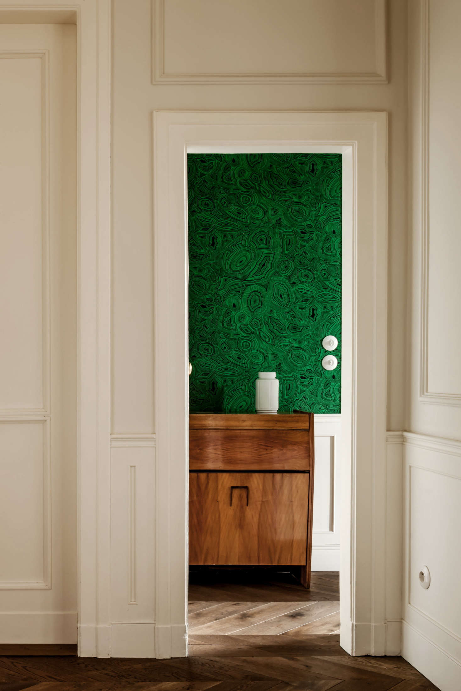“The moldings are not original,” says Chrapka. “I added them, but they were made in the oldest factory in Warsaw in accordance with traditional methods.” Just beyond this space, a Cole & Son malachite wallpaper packs a visual punch.