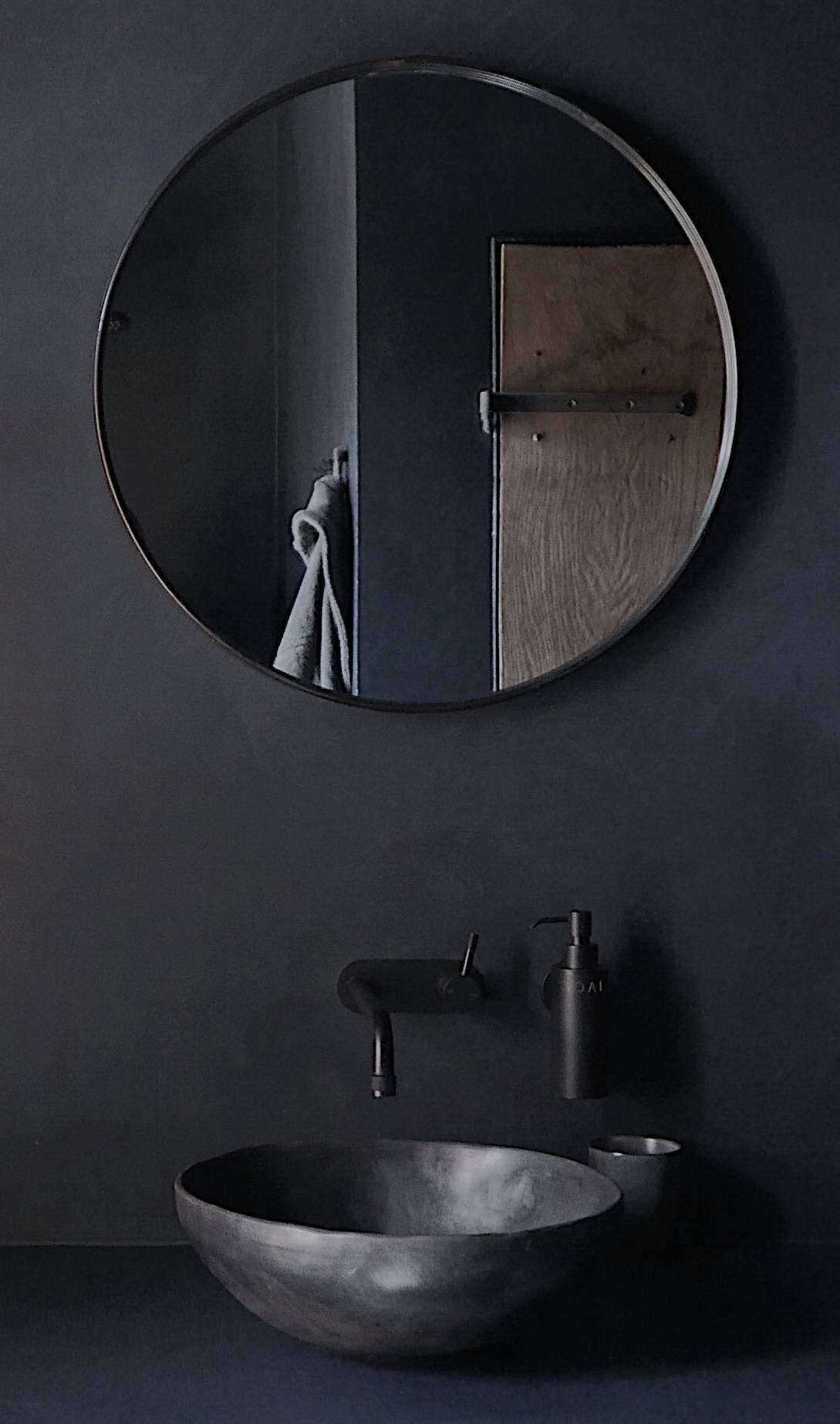 A sculptural ceramic basin from Joris Van Apers paired with a wall-mounted matte-black faucet from Phoenix.