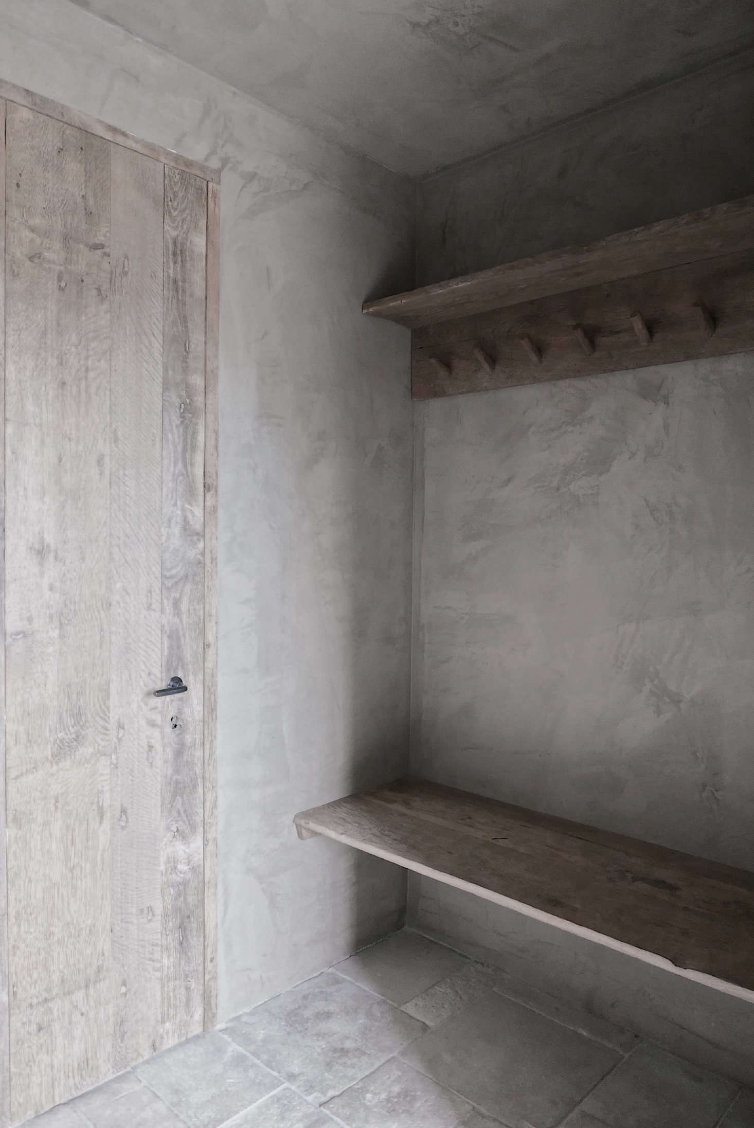 The entrance to the Gairnshiel sauna with a door, bench, and hooks of reclaimed wood. The stone floor is original.