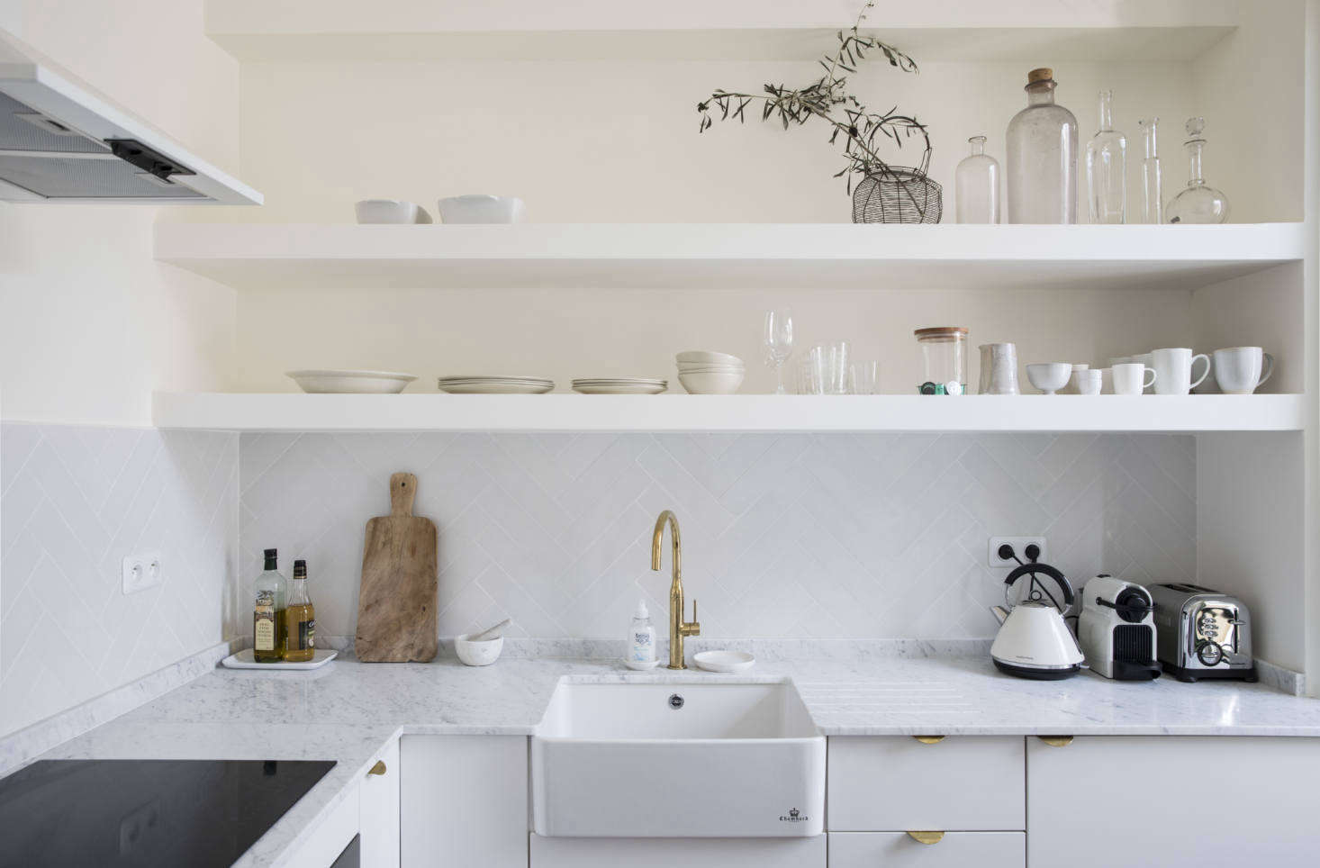 The farmhouse kitchen sink is from Darty and the white extractor hood is from La Peyre. The counters are Carrara marble sourced from Marbrerie Provencal.