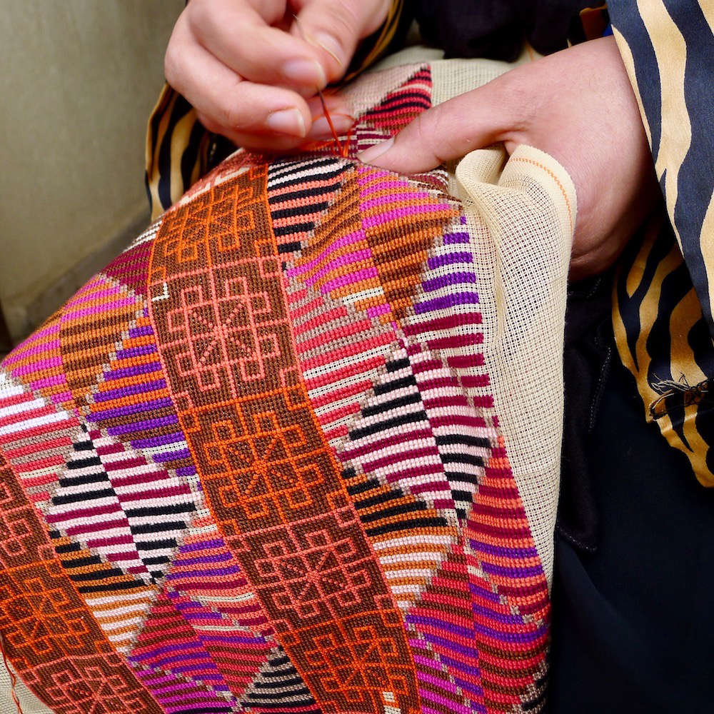 No pattern is printed on the canvas; the craftswomen either consult images of the design or embroider from memory.