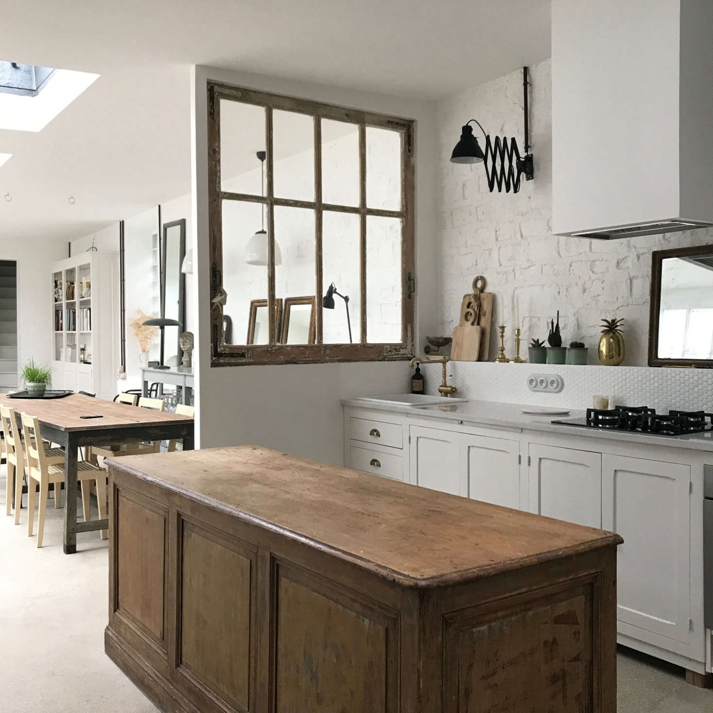 “All of the furniture and decor in the house was discovered by Brice and myself at professional antique markets,” says Brun. The couple also works with demolition companies to salvage interesting pieces, like this oversized vintage window that separates the kitchen from the open living room.