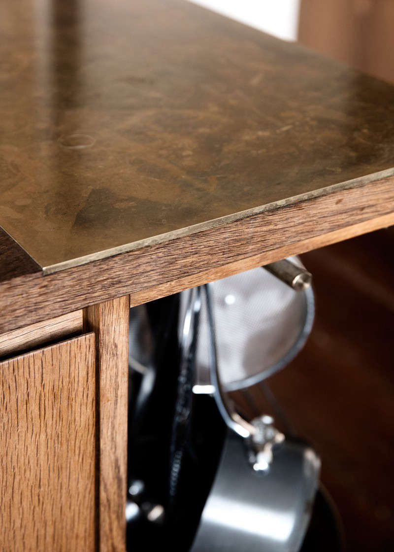 At the end of the island opposite the stove, a section of the counter is topped with brass for setting down hot pots.
