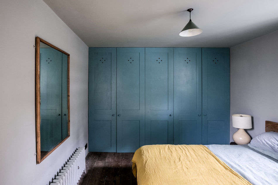 A wall of blue closets anchors this bedroom.
