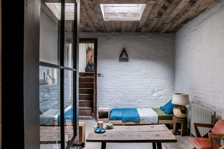 A short flight of steps from the dining area leads down to the living room. A skylight in the reclaimed-wood ceiling provides some natural light. The colors you see here—blue, green, and red—are echoed throughout the house to cohesive effect.