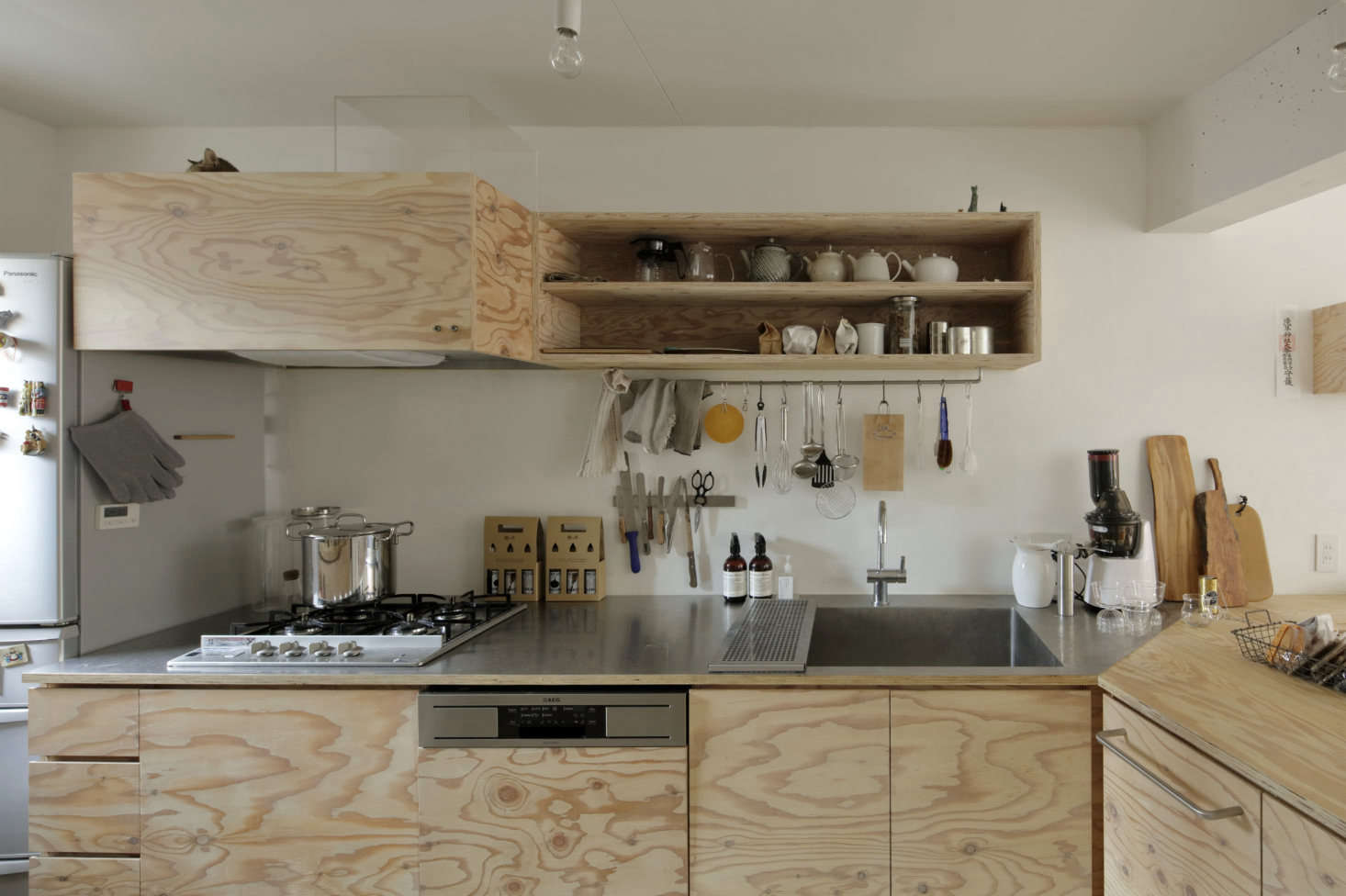 The cabinets are faced with lauan plywood finished with a translucent white Osmo Wood Wax, and the counters are a combination of thin stainless steel and plywood.