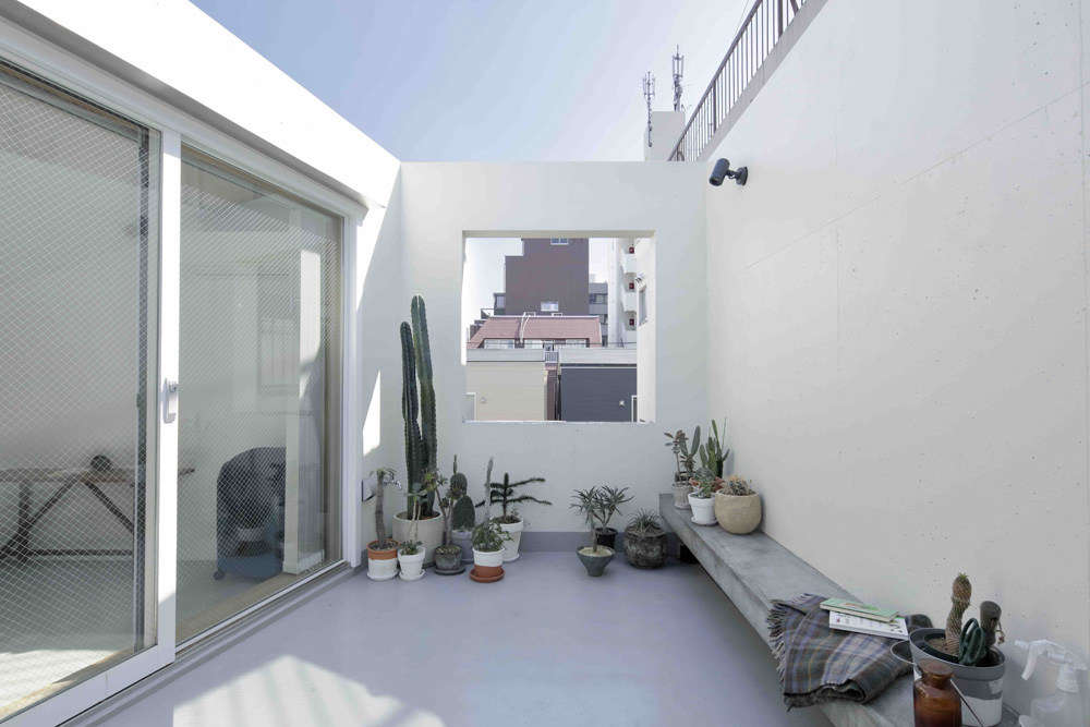 The whitewashed roof deck features a concrete bench and a framed view. Mia told us friends have commented that it reminds them of the roof terrace in the Luis Barragán house in Mexico City.