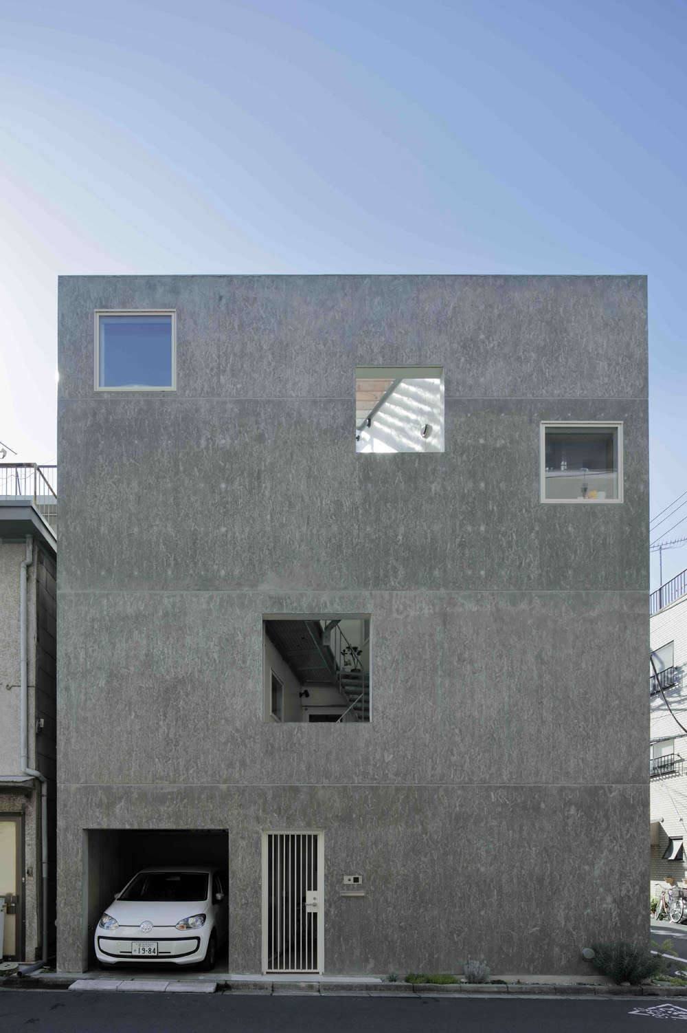 A garage and side entrance are neatly integrated into the northern side of the building. The two unglazed windows expose the structure