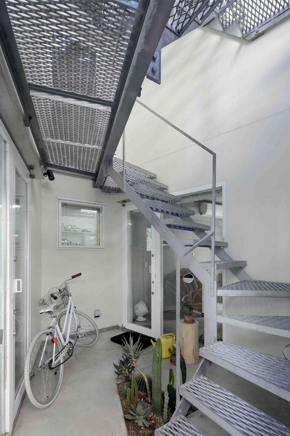 The entrance next to the garage opens to a pocket-size succulent garden next to the steel mesh stair. The ground floor houses a commercial kitchen and showroom for Cineca, Mio