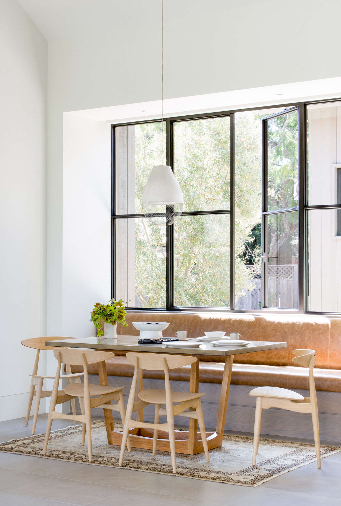A breakfast nook features a built-in leather banquette. The pendant light is the Open Meshmatics Lamp by Atelier Rick Tegelaar.