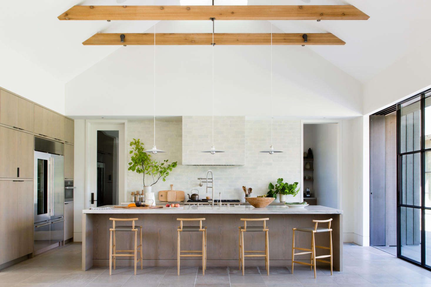 The kitchen features pale Cloud Tile by Portland, Oregon-based Tempest Tileworks and a trio of Brendan Ravenhill pendants over the island. The island countertop is Mandarin white-honed limestone.