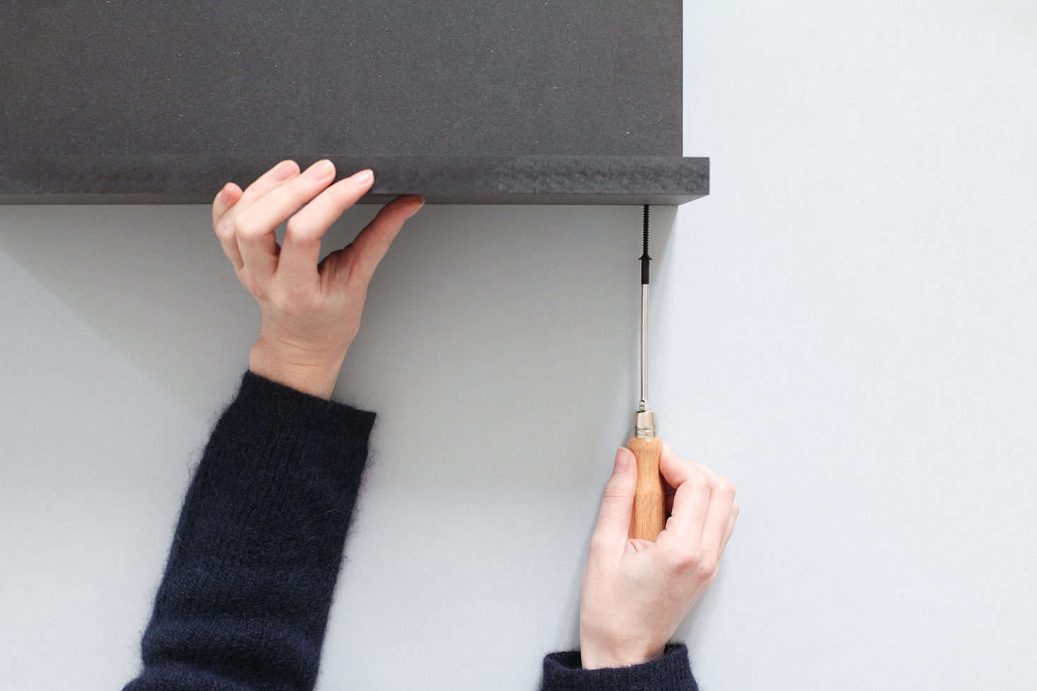 Drill 8-millimeter-wide holes into the top and bottom panels, 3.5 centimeters from the edge (one hole in the center and one at each end). Widen the holes as needed with your drill and screw the bottom panel to the back. N.B.: The designers recommend using black screws.