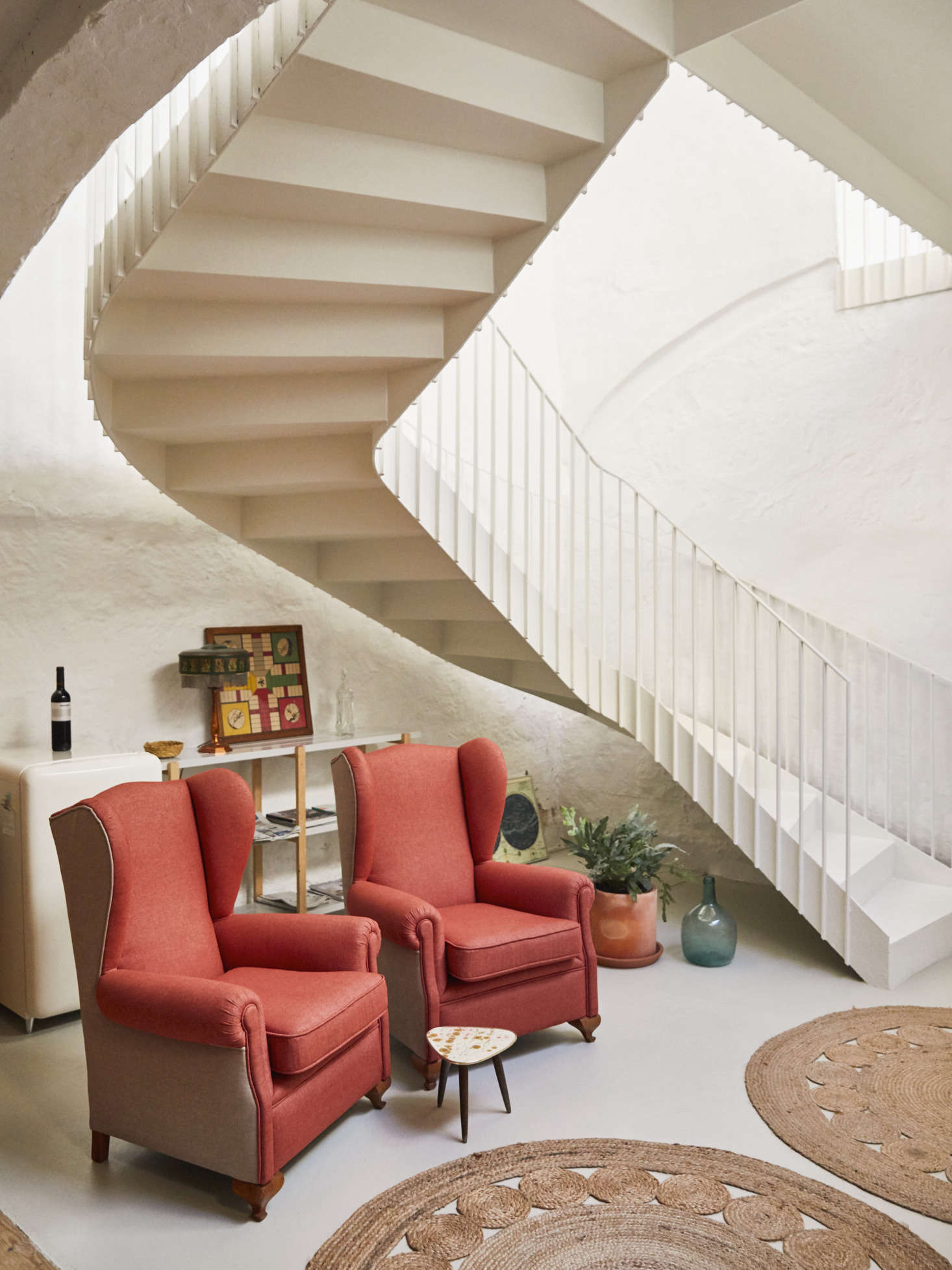In the basement kitchen and lounge area, two vintage armchairs reupholstered by Archimoldi, a firm out of Barcelona. The mini fridge behind them is the Klarstein PopArt-Bar Minibar Fridge and circular jute rugs are the Dandelion Rugs from Armadillo & Co.