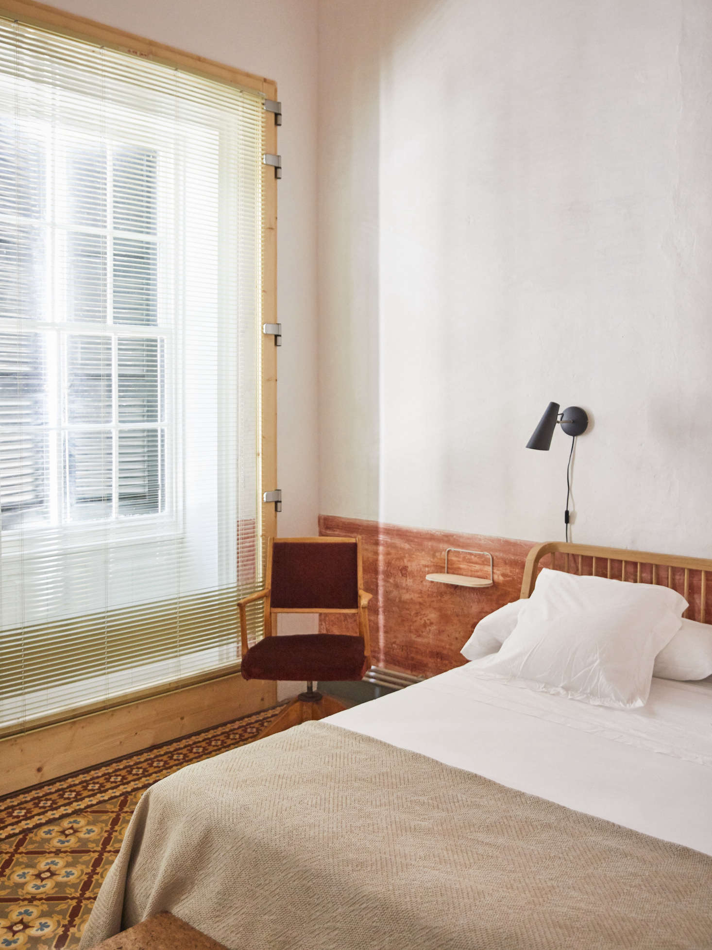 In order to maintain the building’s original façade and the th century guillotine windows, the owners and architect Emma Martí came up with a wood and steel window frame design for improved insulation. The bed frame is the Ethnicraft Spindle Bed in white oak and the wall-mounted light is the Birdy Wall Light by Birger Dahl from 5
