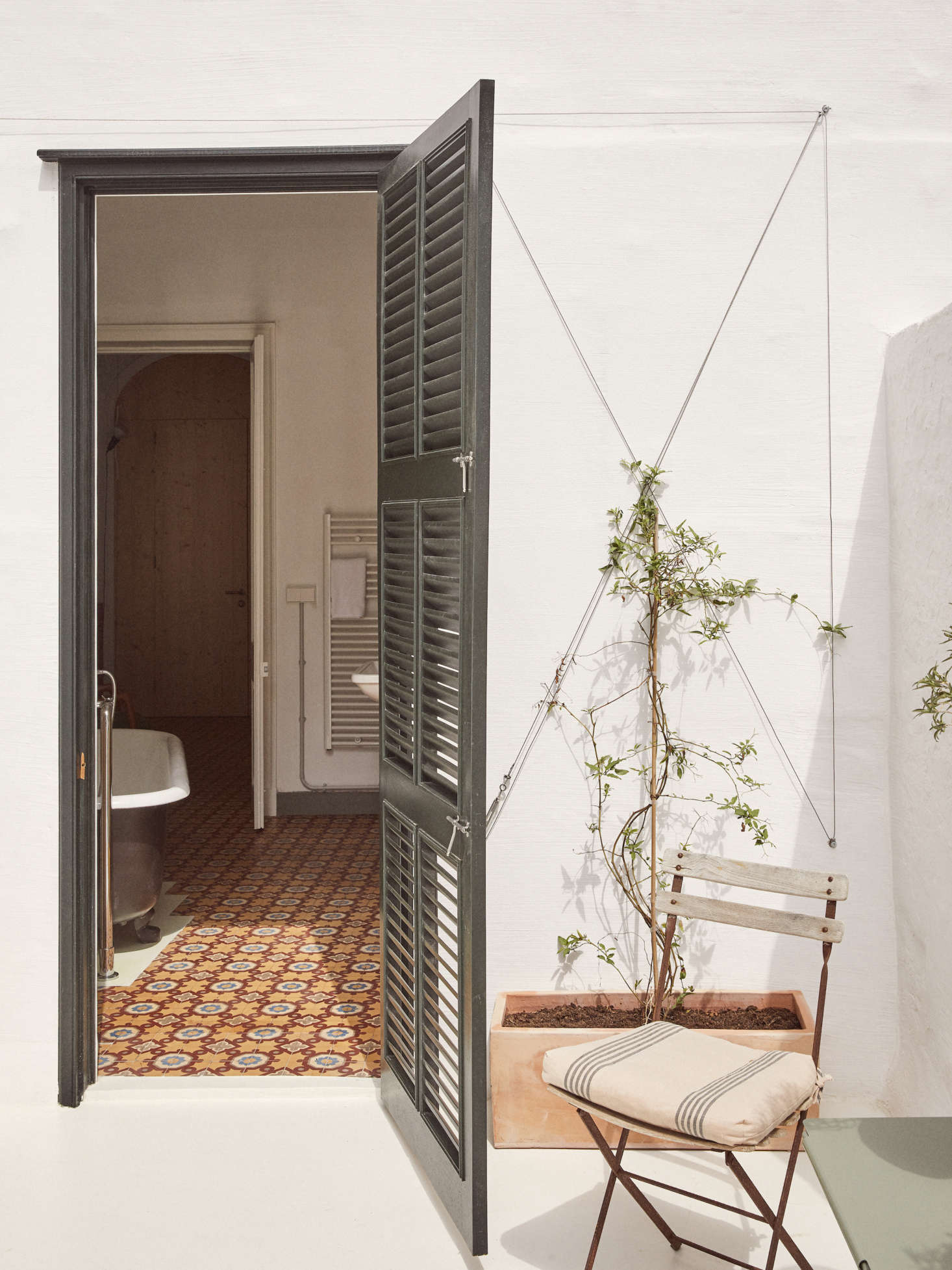 A private balcony off the guest room bath with more terra cotta by way of new planters, and in-progress vines trailing up the plaster walls.