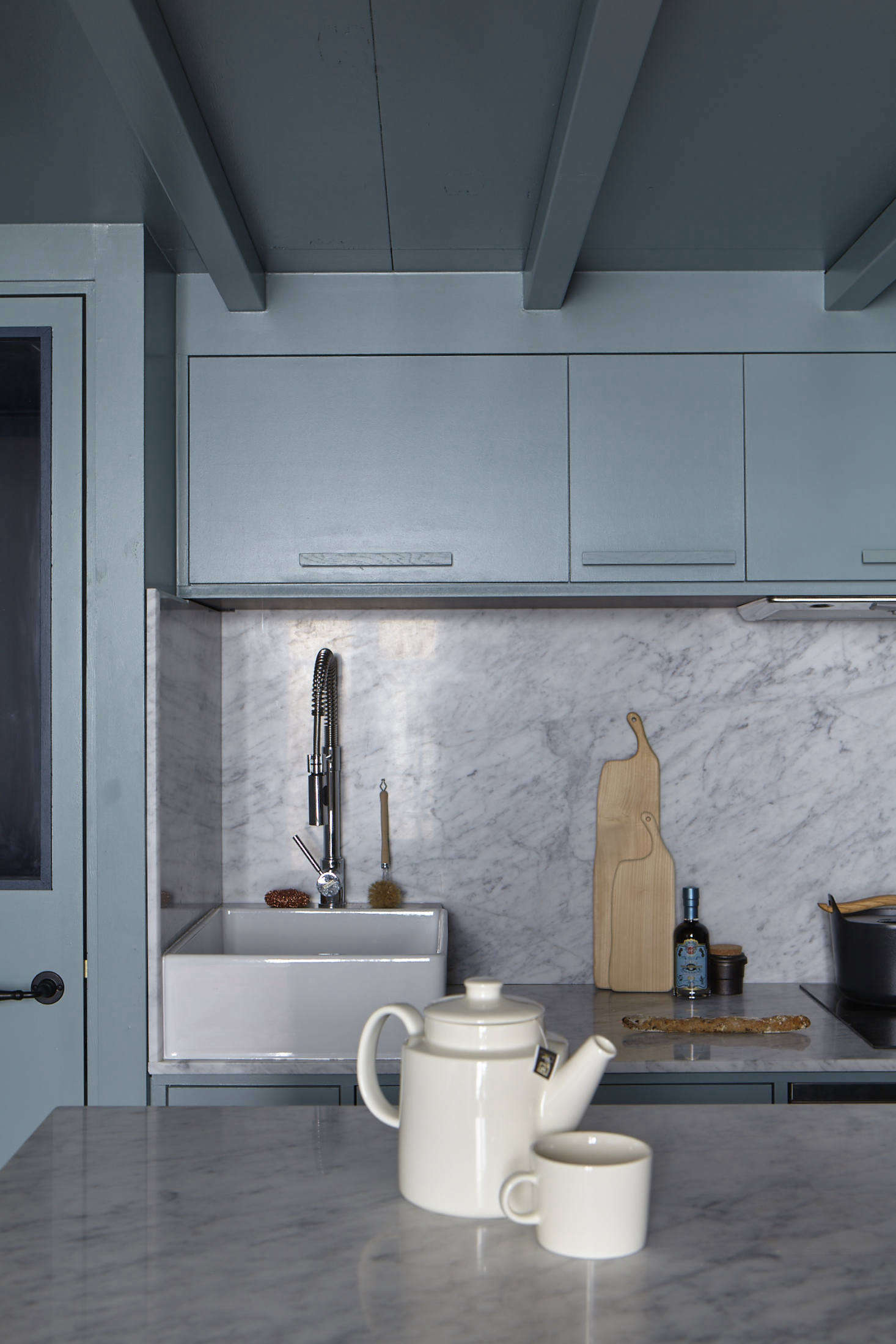 The well-fitted kitchen features counters that continue into a solid backsplash, making the space feel larger and more cohesive (see Favorite Solid Marble Kitchen Backsplashes for more ideas). The sink is what Evennou calls a 