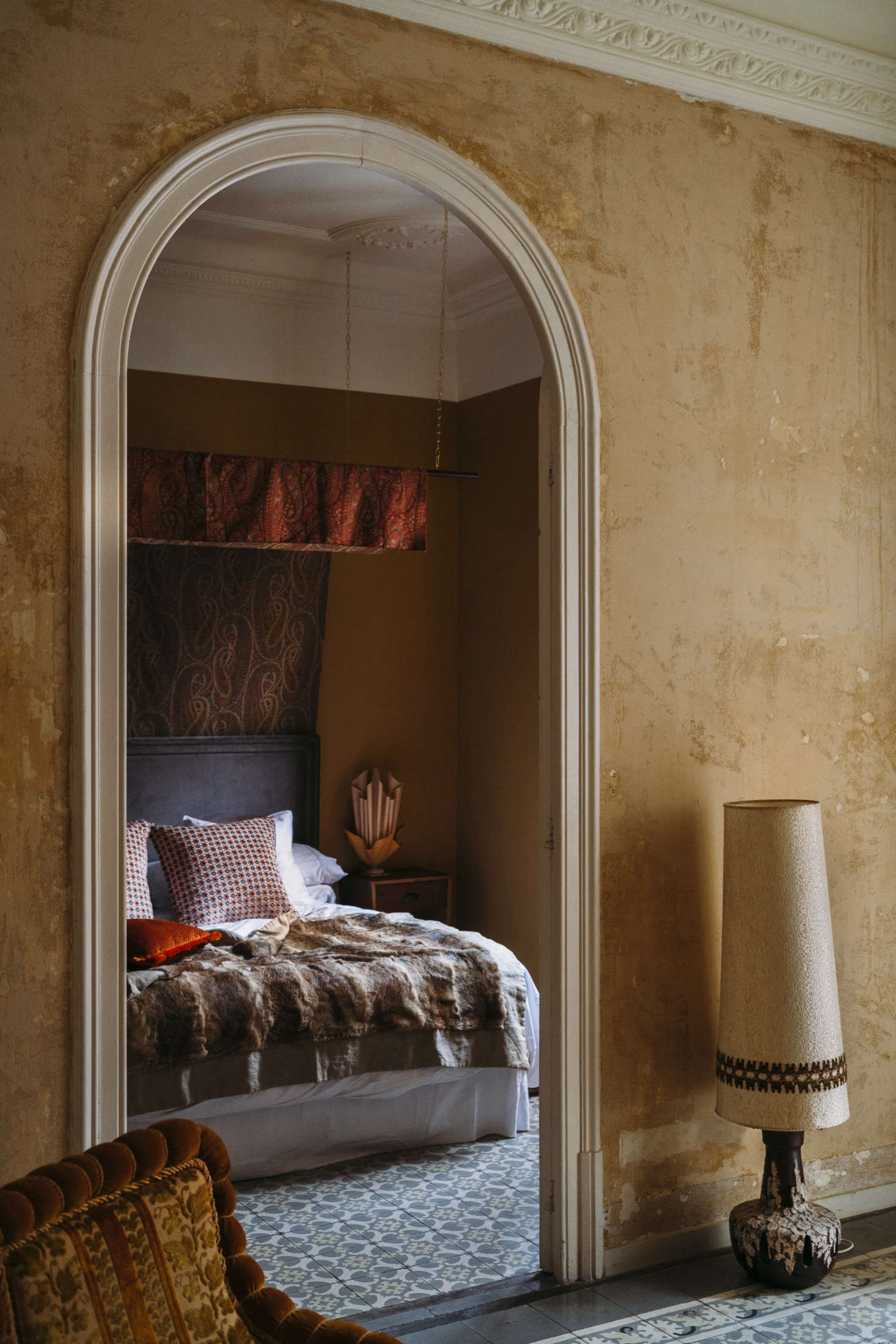 The hallway walls were stripped down to their first layer of paint and the original cement floor tiles were preserved. In the master bedroom, a homemade paisley canopy hangs against an unusual upper wall treatment.