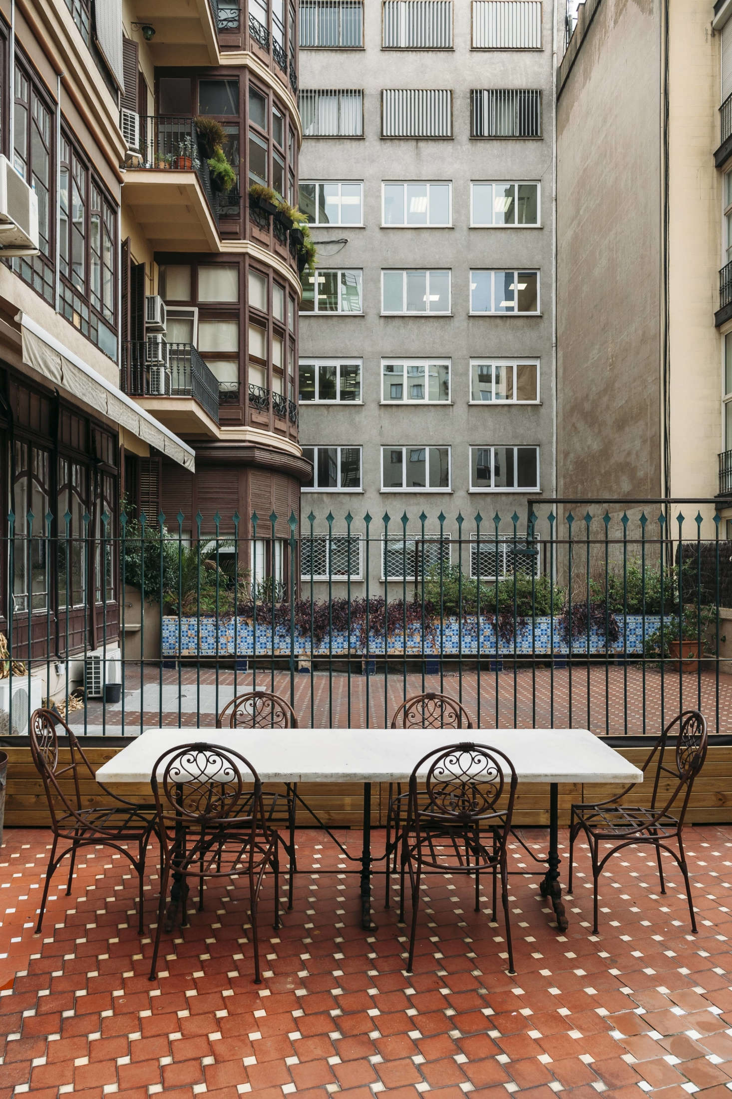 A marble-topped table and iron chairs on the terra-cotta tiled terrace with a rear-window view.