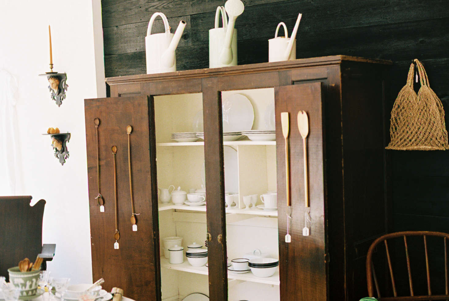 Wares are displayed like they would be in a home; here, Long-Stemmed Double Teaspoons ($65) and Flat Spatulas, made in Brooklyn ($60), are hung on the doors of a wooden hutch. The woven bag is the Abaca Mini Eco Tote ($24).
