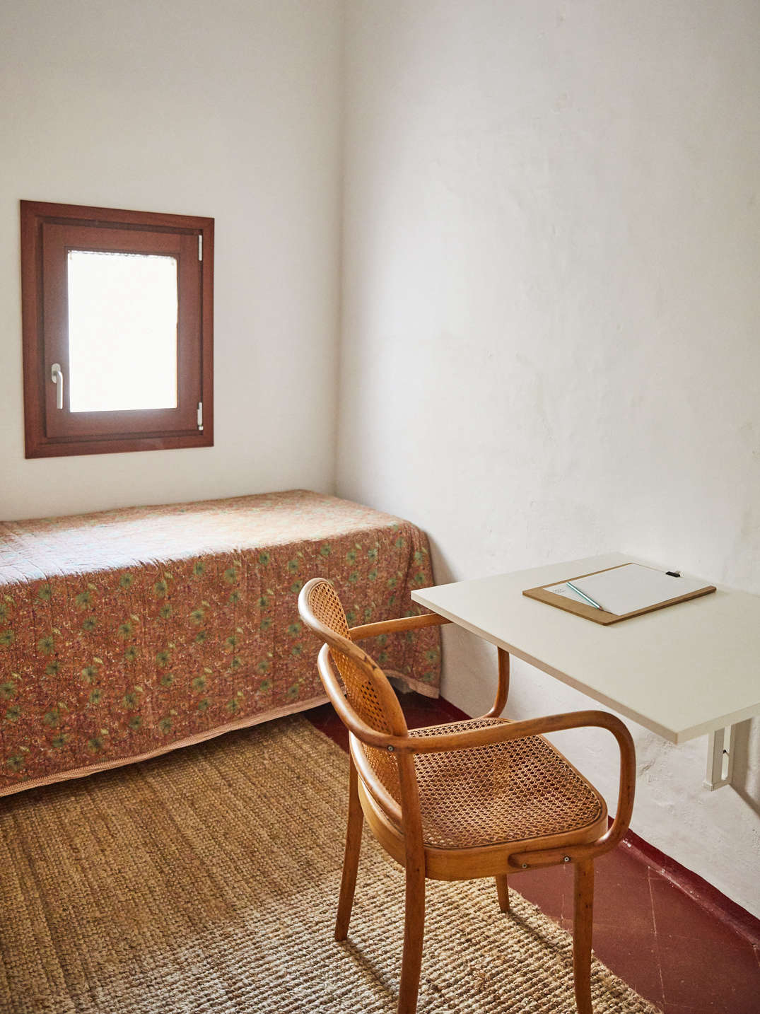 In a small upstairs guest room, a vintage Joseph Hoffmann Armchair and the Ikea Norberg Drop-Leaf Table makes an instant desk. At the foot of the chair is the jute Lohals Rug, also from Ikea.