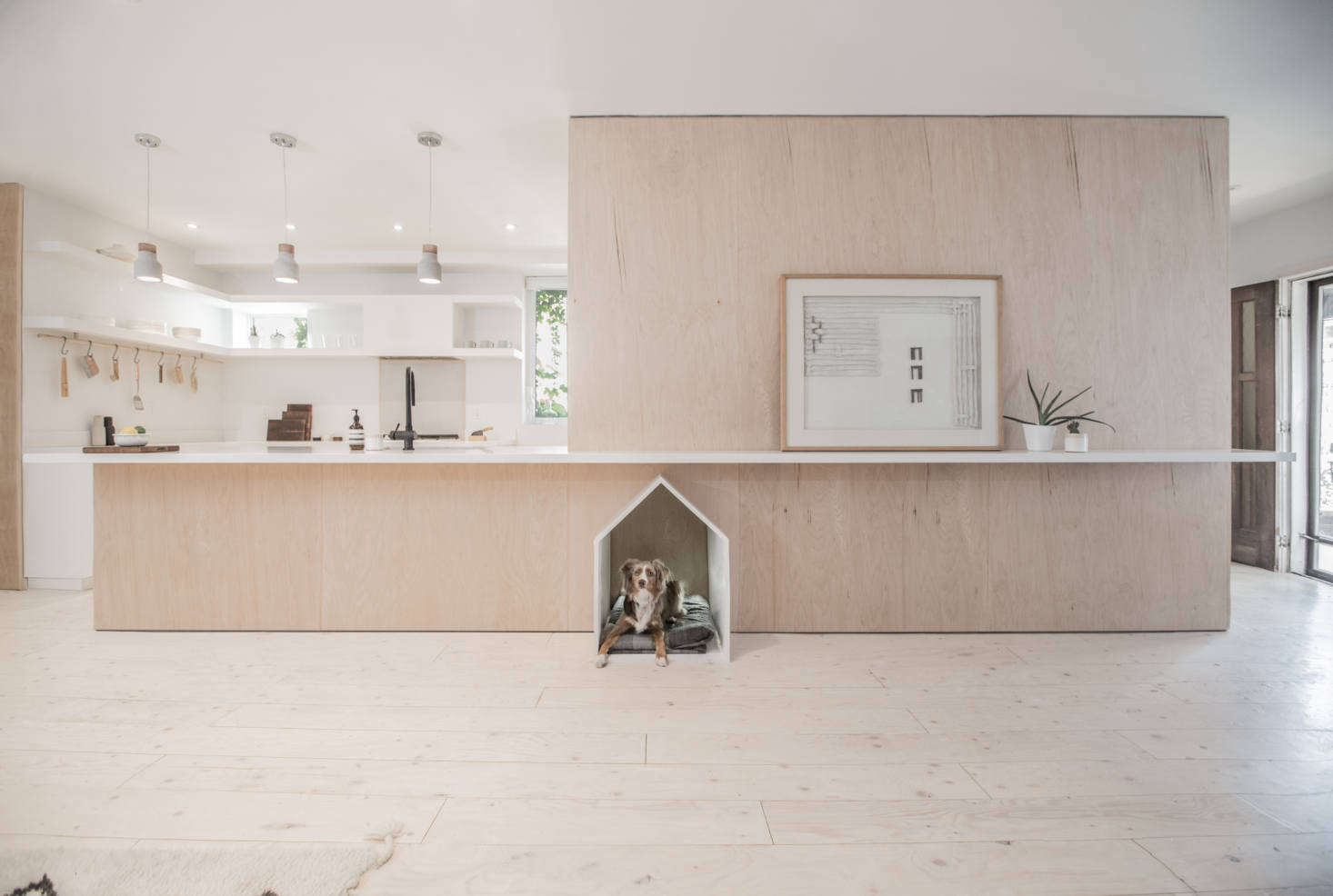 “Rather than imagine a home comprised of rooms within an open plan, we conceived a room revolving around a singular mass,” write the architects. “The mass provides the aesthetic grounding for the project while also containing all of its support functions in a clean plywood wrapper.”