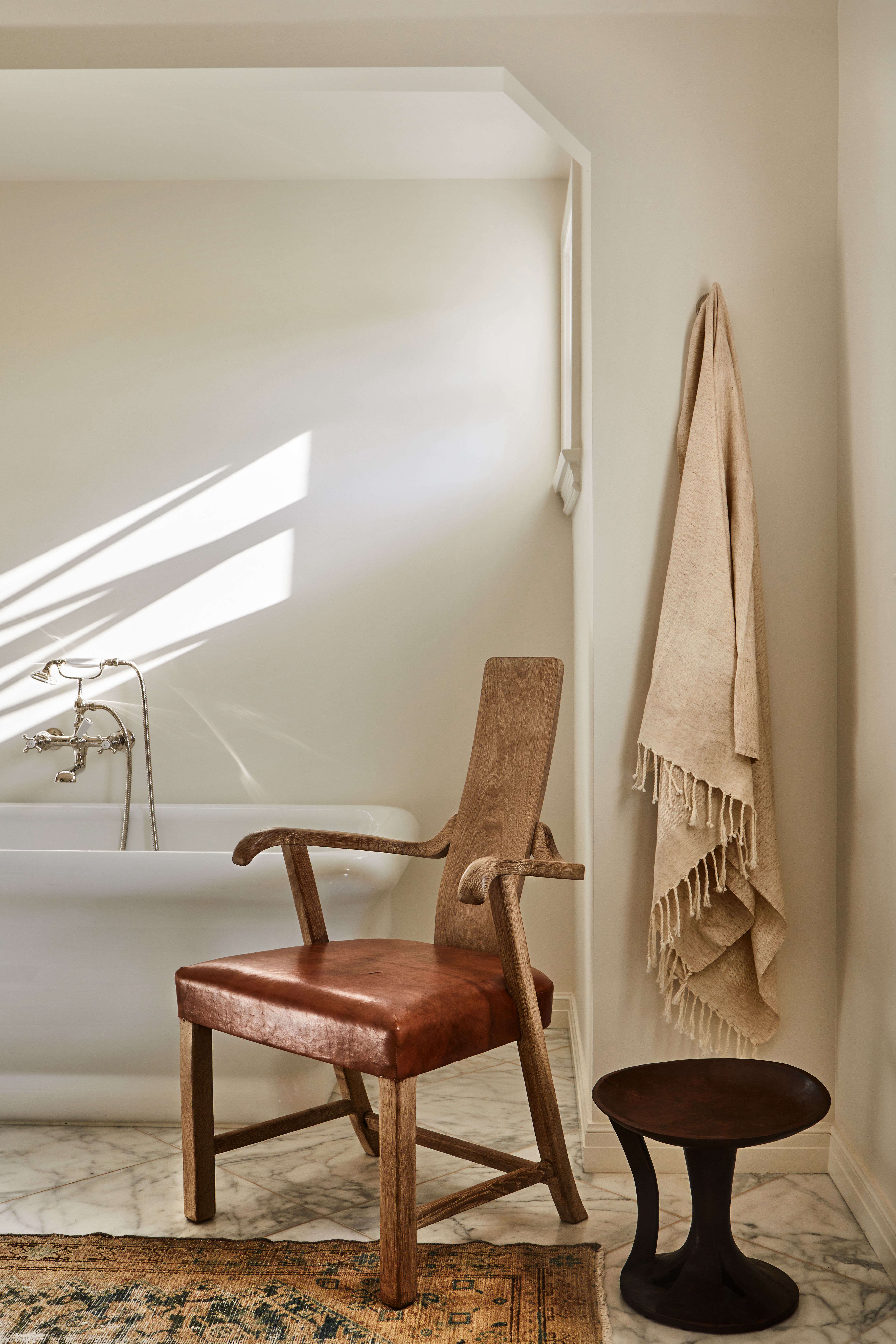 A Lucca Antiques chair—does it look like a seated person to you?—stands next to an African stool. The walls are painted Benjamin Moore White Dove. 
