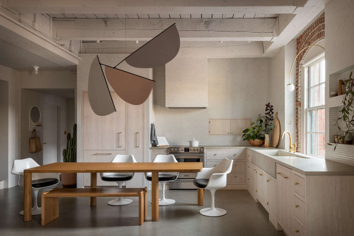 The kitchen, with the entryway just behind, has glimpses of the old—red brick, an arched window—among the new, including a custom concrete countertop and sink by Cement Elegance. A whimsical mobile designed by GamFratesi hangs above the table.