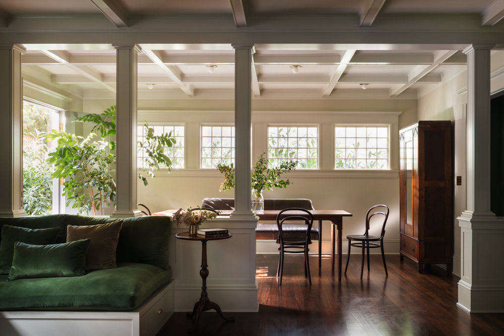 A casual breakfast room is just off the kitchen. The house had been stripped of its period details over the years; the design team made sure to add back in architectural interest, like coffered ceilings and columns. In the forefront is the family room.