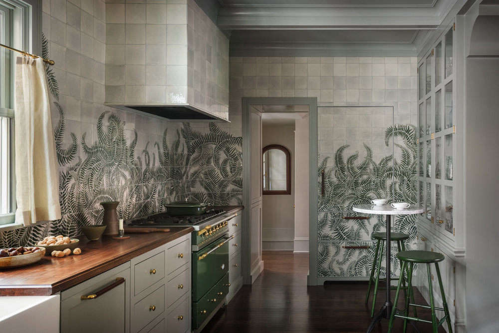 The mural extends to every wall in the kitchen—and even covers the built-in refrigerator “to achieve a seamless fern-scape throughout the room,” she says. “Our clients were onboard with our aesthetic direction for the house, which was ‘an ode to the Pacific Northwest.’ This led us toward furniture and decorative lighting that are markedly modern with lush mossy tones and plenty of Western walnut.”