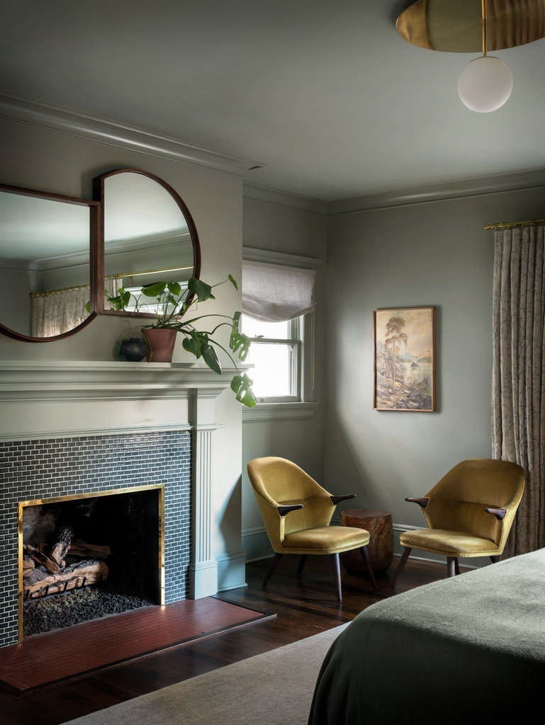 Two mirrors by Marrow hang over the fireplace in the master bedroom. The fireplace surround features handmade ceramic tiles by Pratt and Larson. The walls are painted Benjamin Moore Heather Gray.
