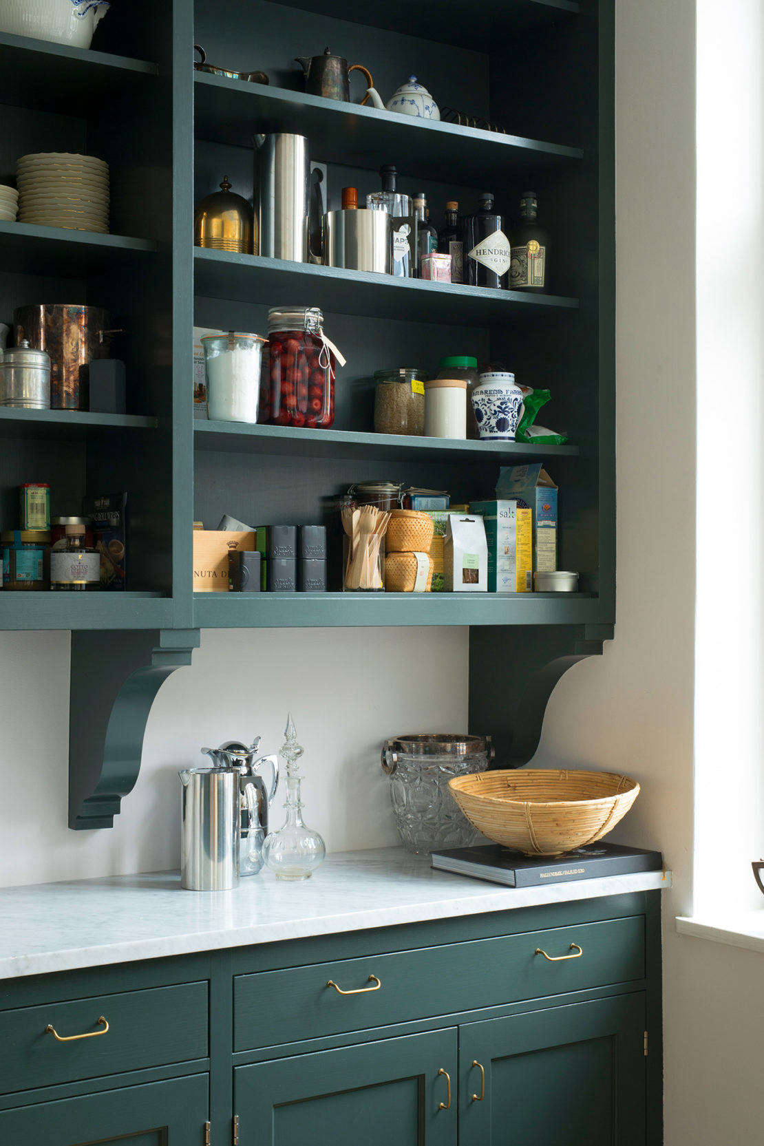 The bracketed shelves are usually faced with framed-glass cabinet fronts, but are here left open—Sara refers to them as 