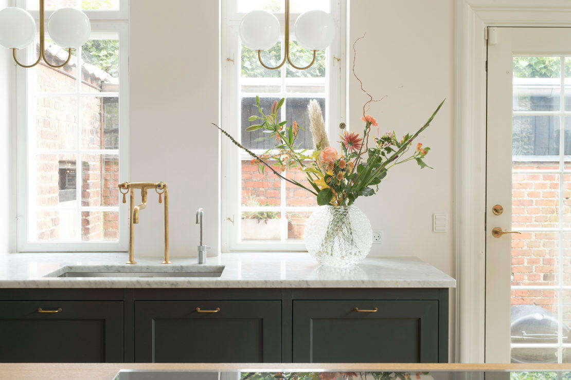 Set in a Carrara marble counter, the sink has a show-stopping brass mixer faucet from Danish brand Toni Amatur. The brass and opal glass globe ceiling fixtures are Michael Anastassiades