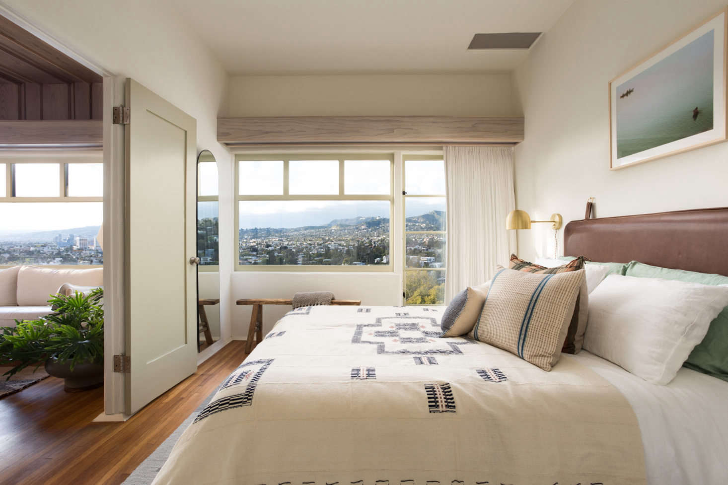 The small bedroom features linen bedding by Five/Six Textiles, a custom leather-wrapped headboard, and views of Los Feliz. Photograph by Virtually Here Studios.