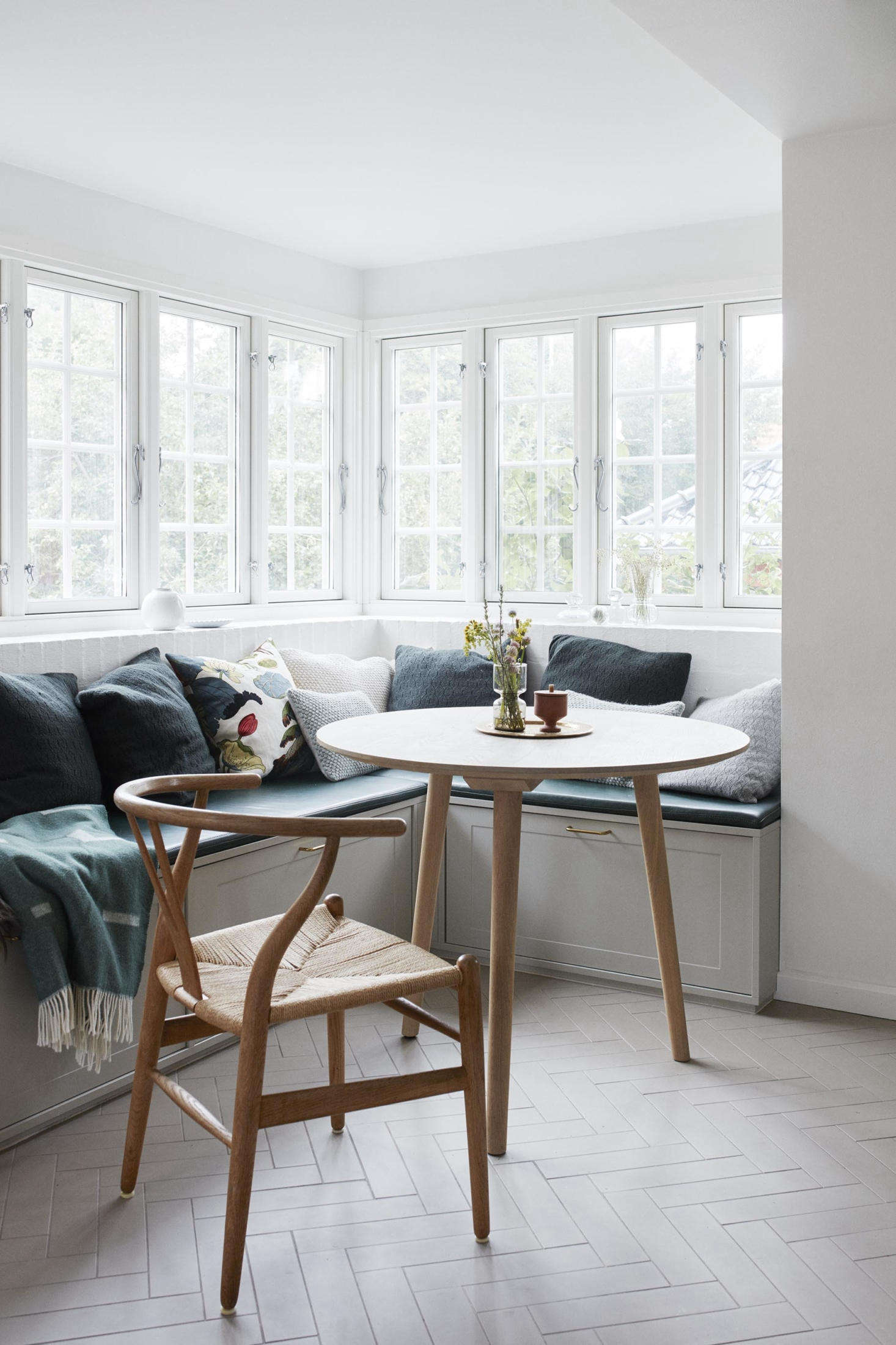 A sunny dining nook provides ample room for the family to gather—as well as storage, tucked underneath. The tile flooring is new, from Original Style, 